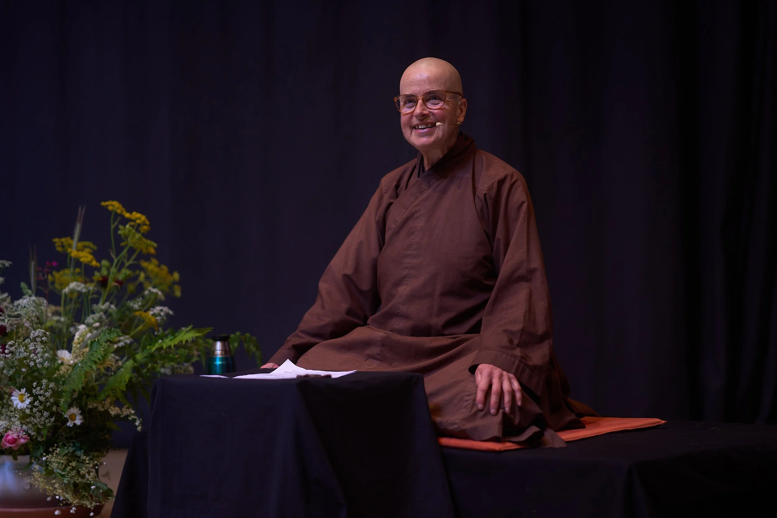 A group of people attending a seminar, with the focus on a smiling, bald man wearing a dark brown jacket.