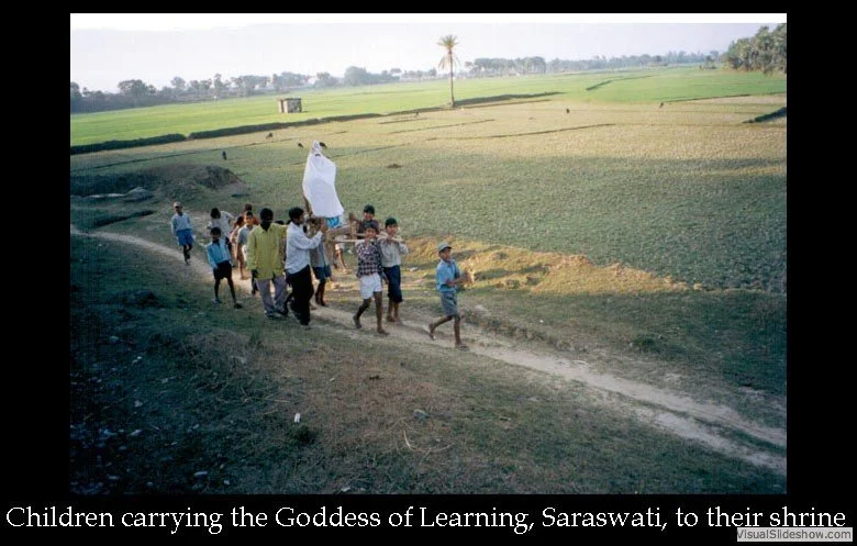Children carrying a figure of the Goddess Saraswati, the Goddess of Learning, to a shrine in a rural area.