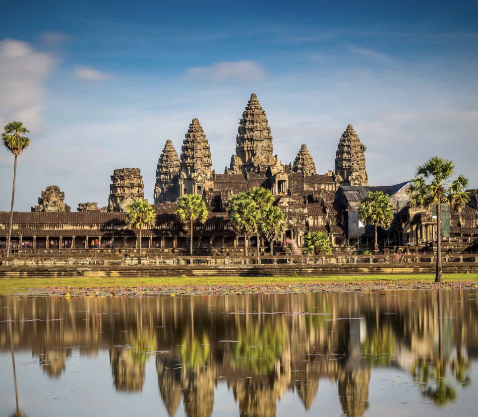 The Taj Mahal in India during sunset, with a symmetrical view reflecting the monument in the water pool, surrounded by minarets and visitors walking around.