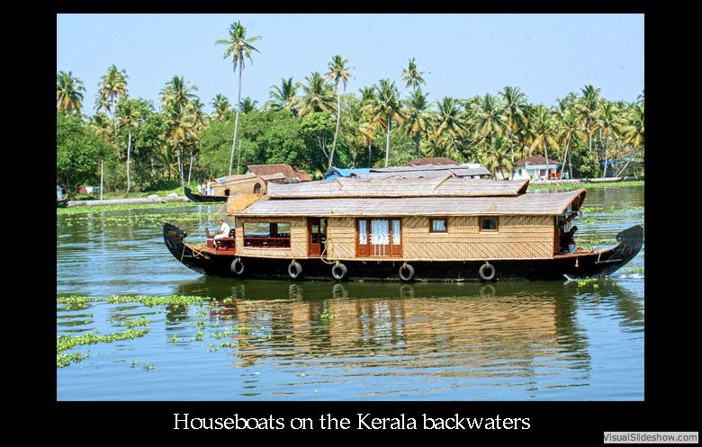 A houseboat on calm water with lush green palm trees in the background, Kerala backwaters, India.