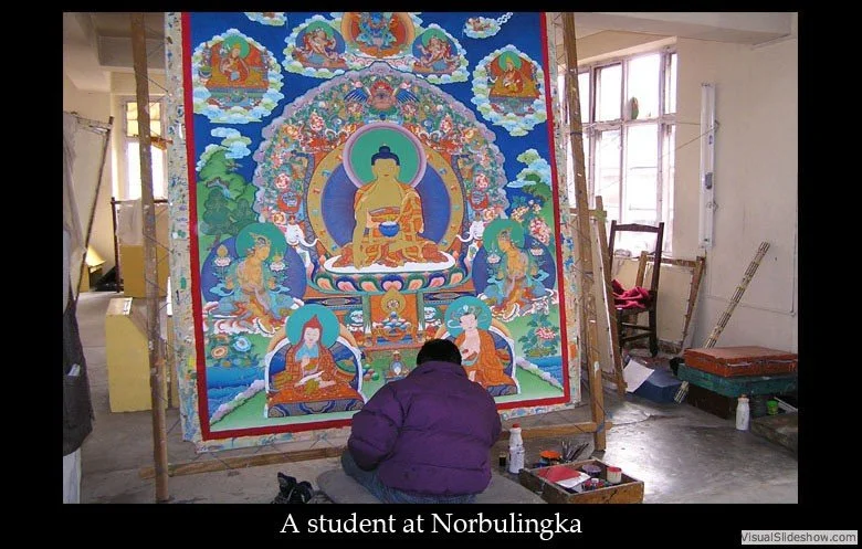 A student in a purple jacket works on a large, colorful Buddhist thangka painting in a studio, with windows and art supplies visible around.