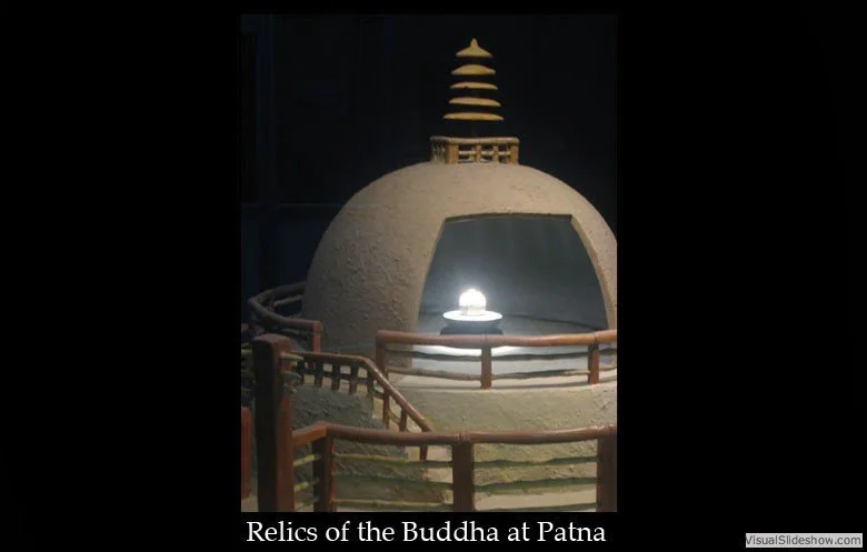 A small replica of a stupa with a dome, surrounded by a wooden railing, with a glowing light inside, labeled 'Relics of the Buddha at Patna'.