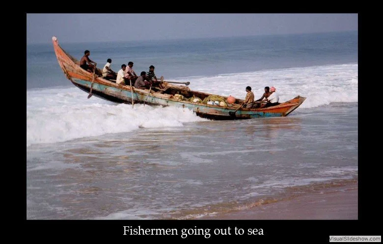 A group of fishermen in a boat heading out to sea through the water.