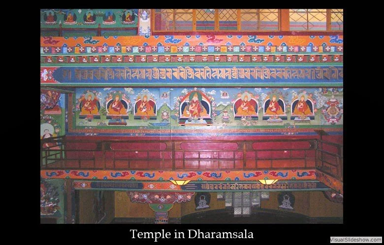 Colorful interior wall of a Buddhist temple in Dharamsala with murals of monks and decorative patterns.
