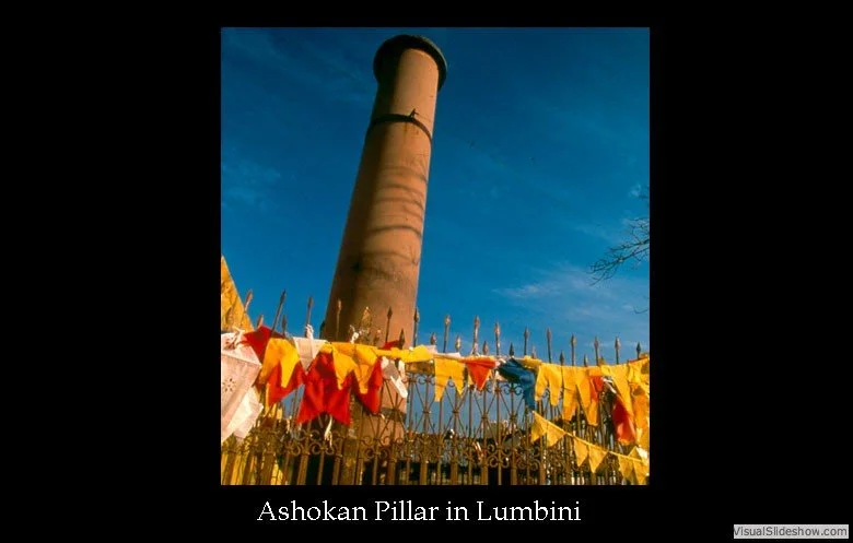 A tall brick chimney standing behind a decorative metal fence adorned with colorful prayer flags. Clear blue sky in the background.