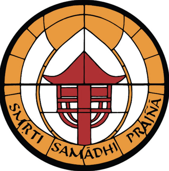 A circular emblem with a black outer border. Inside, there's an orange ring with the words 'SWARITI SAMADHI PRAYNA' written on it. The inner part contains a red stylized lamp or lantern, with a pointed roof and intricate lines beneath.
