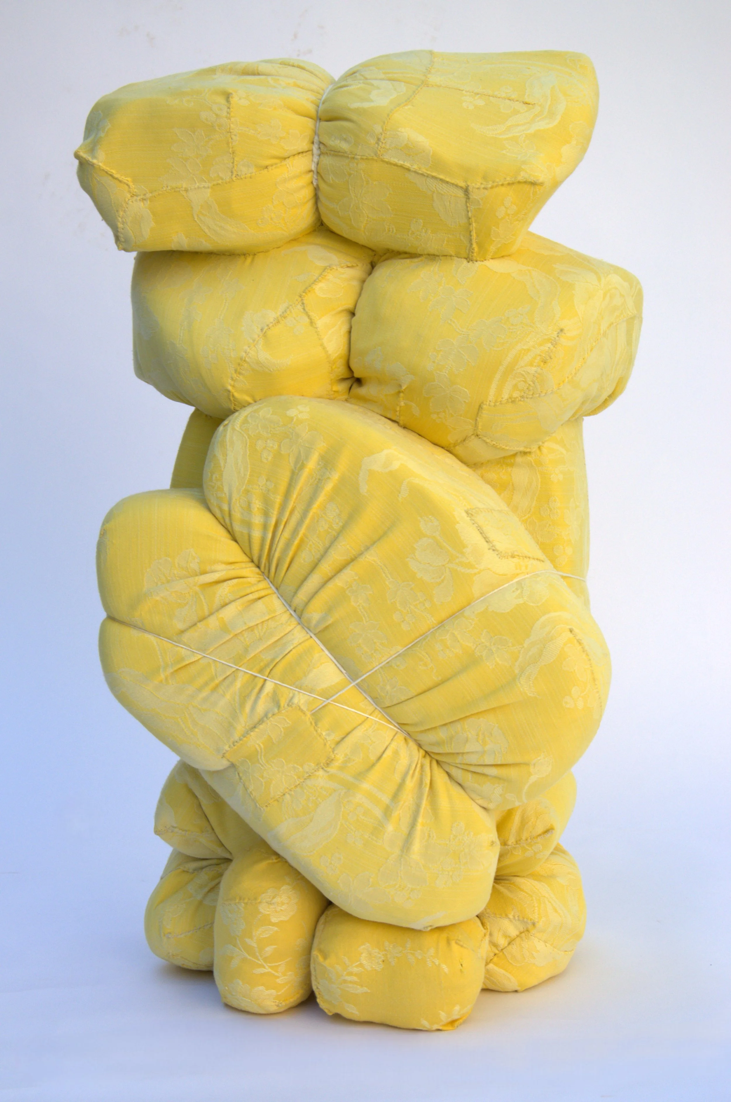  Kristina de Coninck 
 Solace
 Sculpture created from sections of
mattress, dressed with vintage fabrics,
rope and cotton threads
 70 × 40 × 40 cm
 2025
