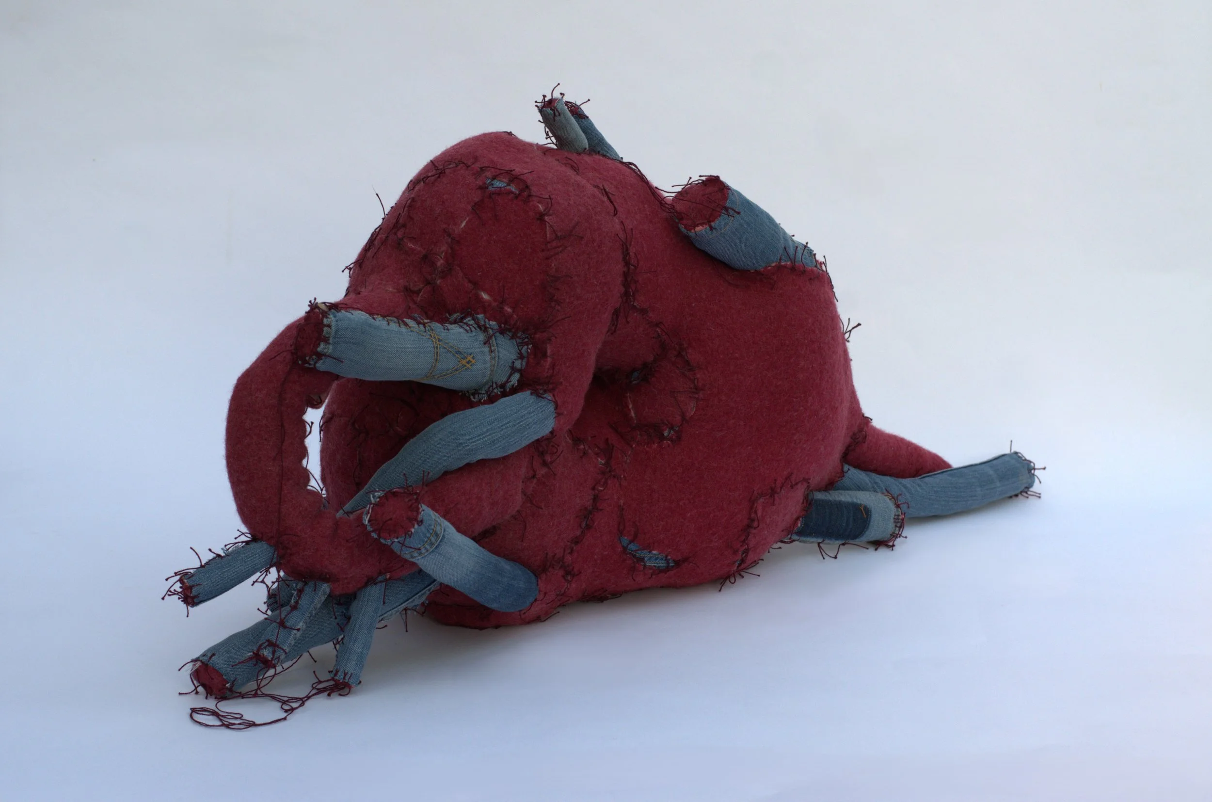  Kristina de Coninck 
 Red wine grape
 Sections of mattress, patches of wool
blankets, denim pants and cotton
threads
 110 × 50 × 35 cm
 2024