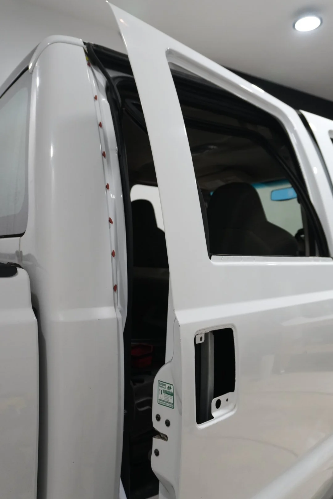 Close-up of a white truck cab with an open door, showing the interior and part of the window.