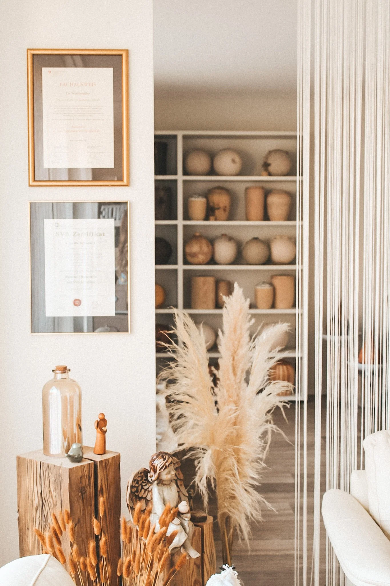 Ein vertrauenswürdiger Ort für Trauerberatung: Unsere Qualifikationen und Zertifikate stehen sichtbar im Eingangsbereich, eingerahmt von liebevoll arrangierter Dekoration und Trockenblumen – ein Ausdruck von Professionalität und Menschlichkeit.