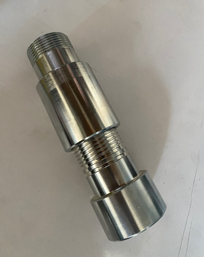 A metallic cylindrical object with threaded ends and a central groove, lying on a white surface.