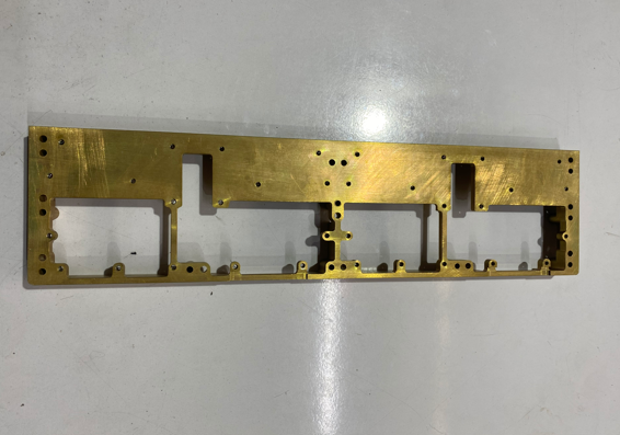 A rectangular metal frame with multiple cutouts and holes, laid flat on a light gray surface.