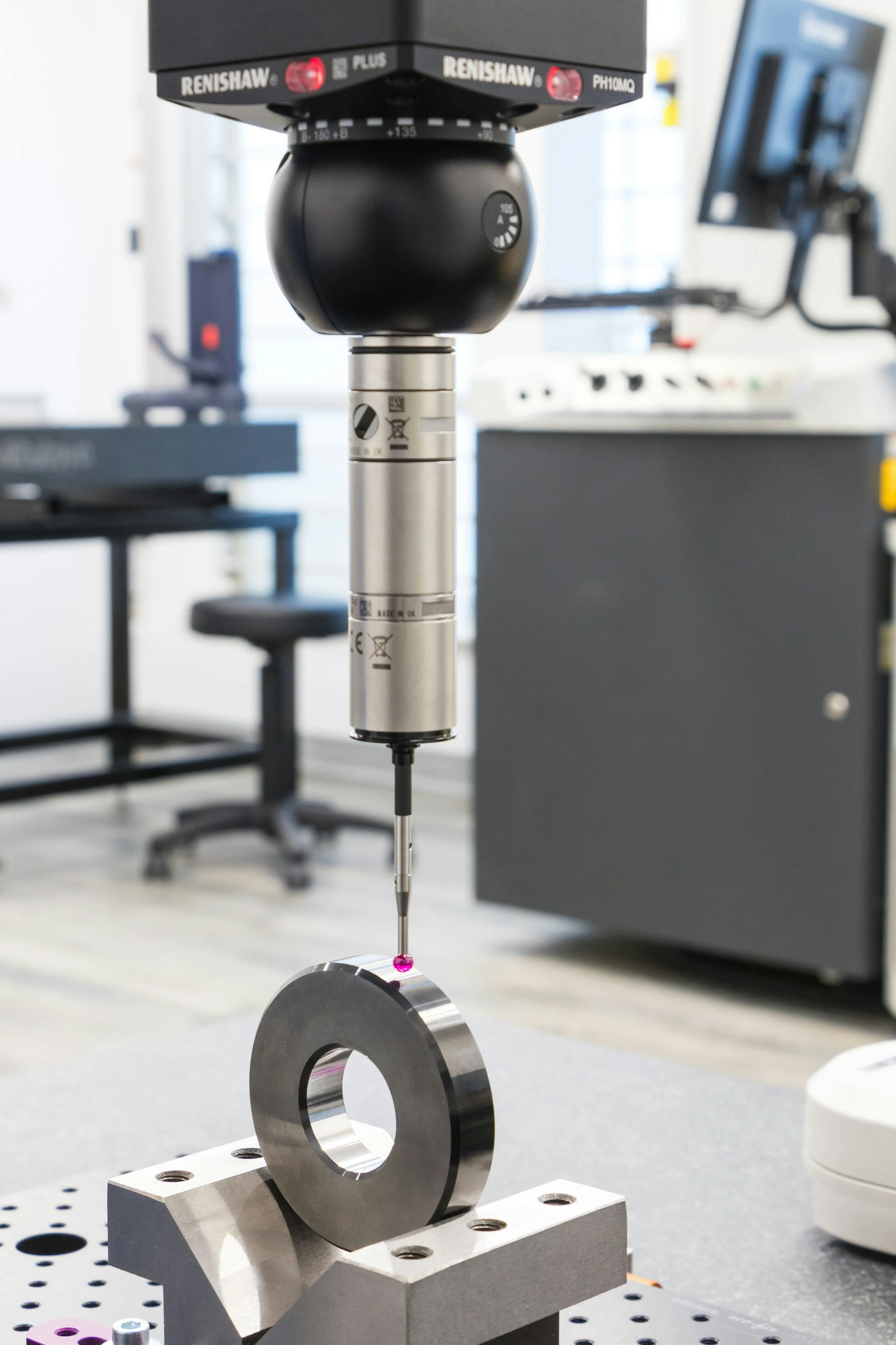 A precision measurement device with a Renishaw sensor above a metal ring, used in a laboratory setting for engineering or scientific experiments.