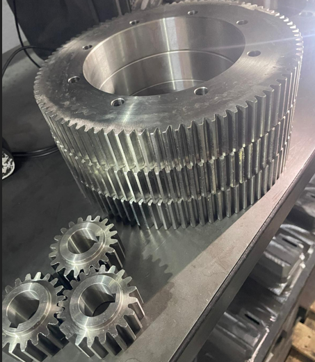 Large metallic gear with smaller gears on a workbench.