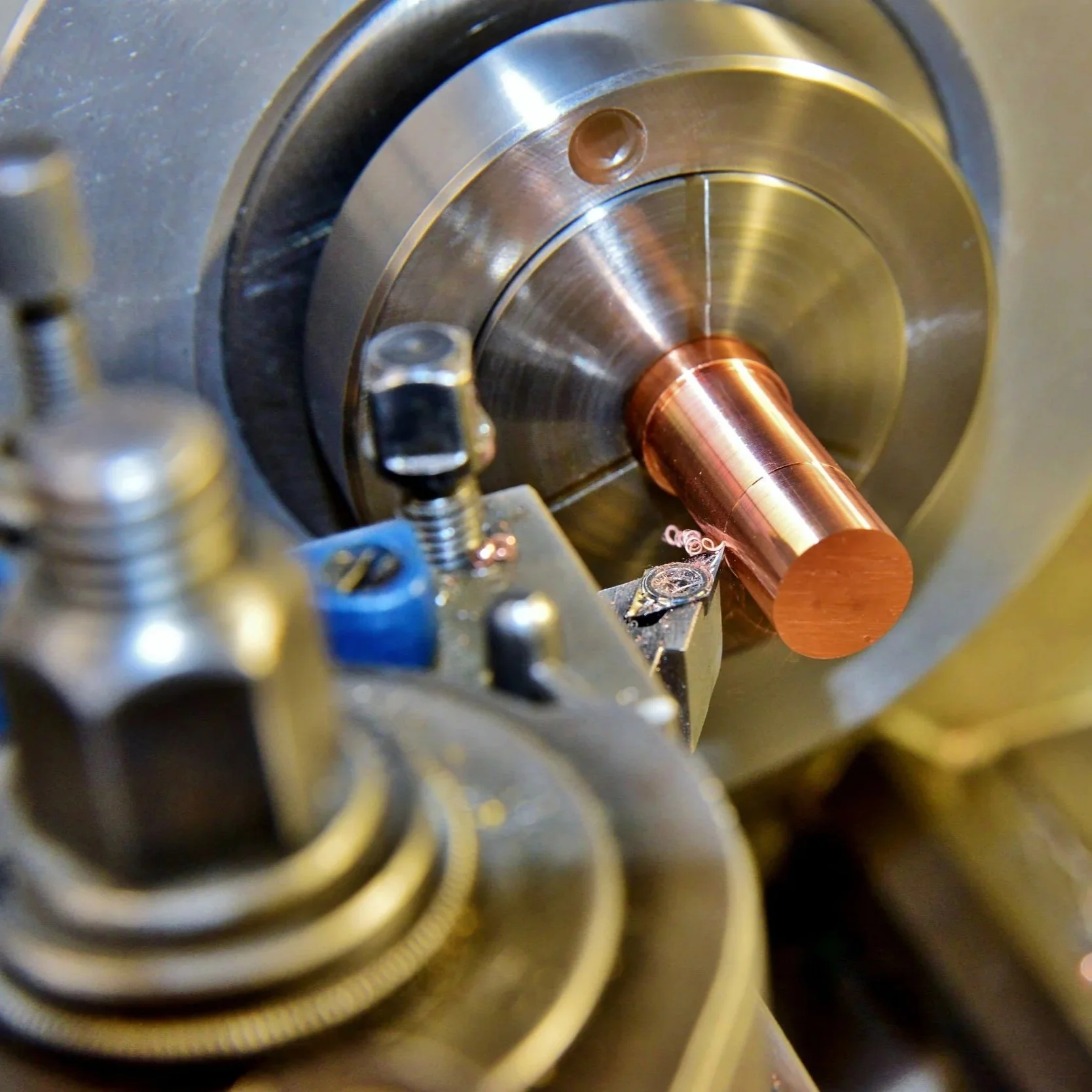 Close-up of a metal lathe machine shaping a copper pipe.