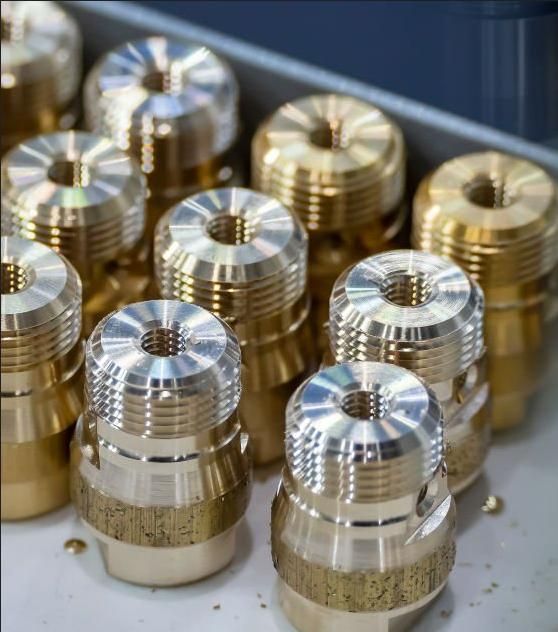 Multiple shiny, metallic, machined components, possibly engine or machinery parts, arranged on a workbench.