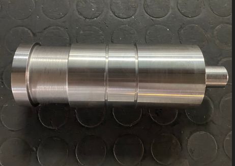 Metal cylindrical object with grooves on a black rubber mat.