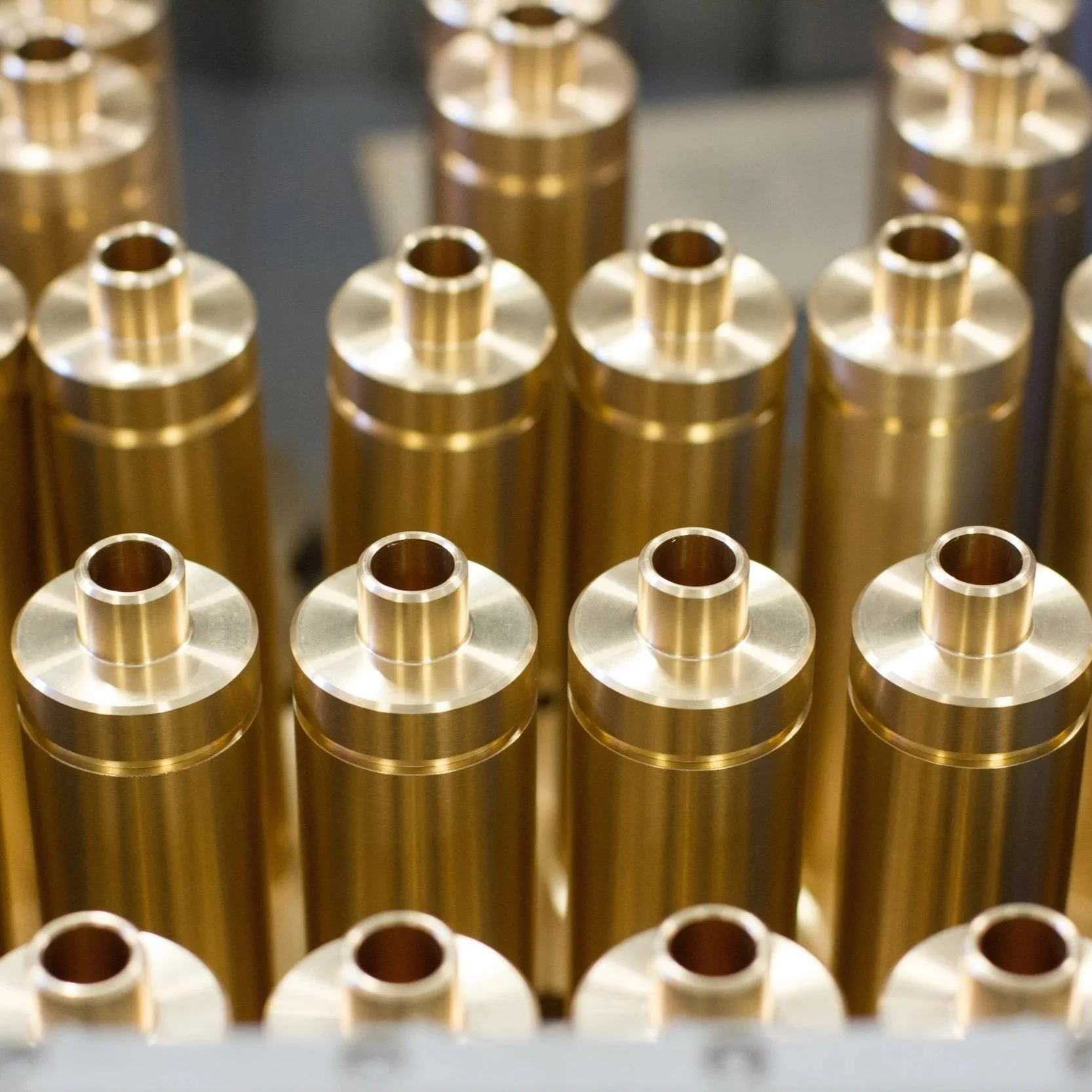 Close-up of multiple gold-colored metal cylindrical parts arranged in rows.
