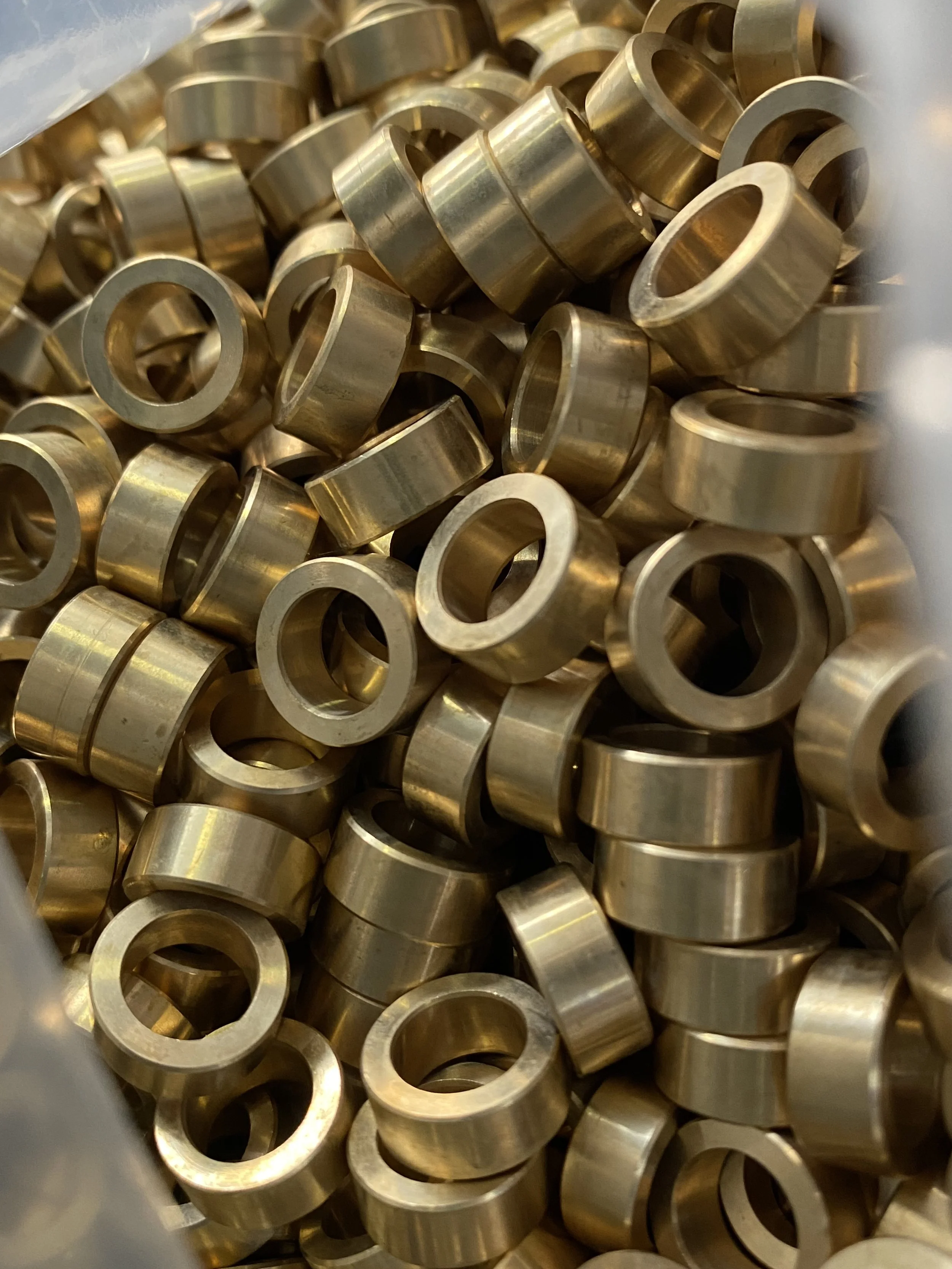 Close-up view of numerous shiny brass or gold-colored metal rings, likely small industrial or mechanical washers or spacers.