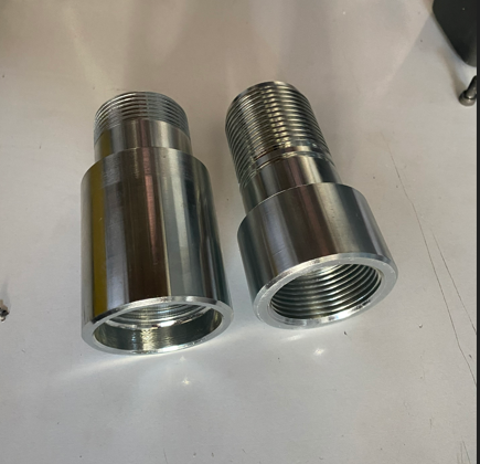 Two large, shiny, metallic threaded cylinders placed on a white surface.
