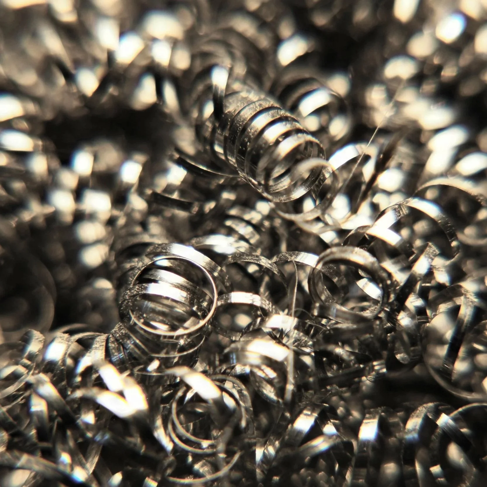 Close-up of numerous small, shiny metal coil springs piled together.