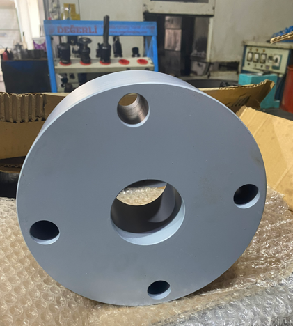 Close-up of a large, circular metallic mechanical part with multiple holes, placed on bubble wrap in a workshop.