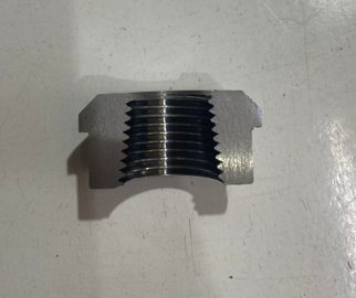 Close-up of a metal threaded pipe fitting on a white surface.