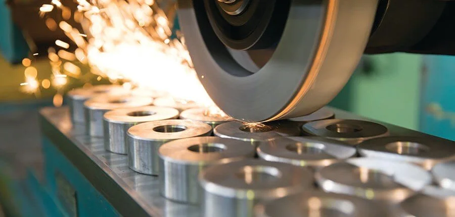 A grindstone cutting through metal components, sparks flying in a manufacturing or machining process.