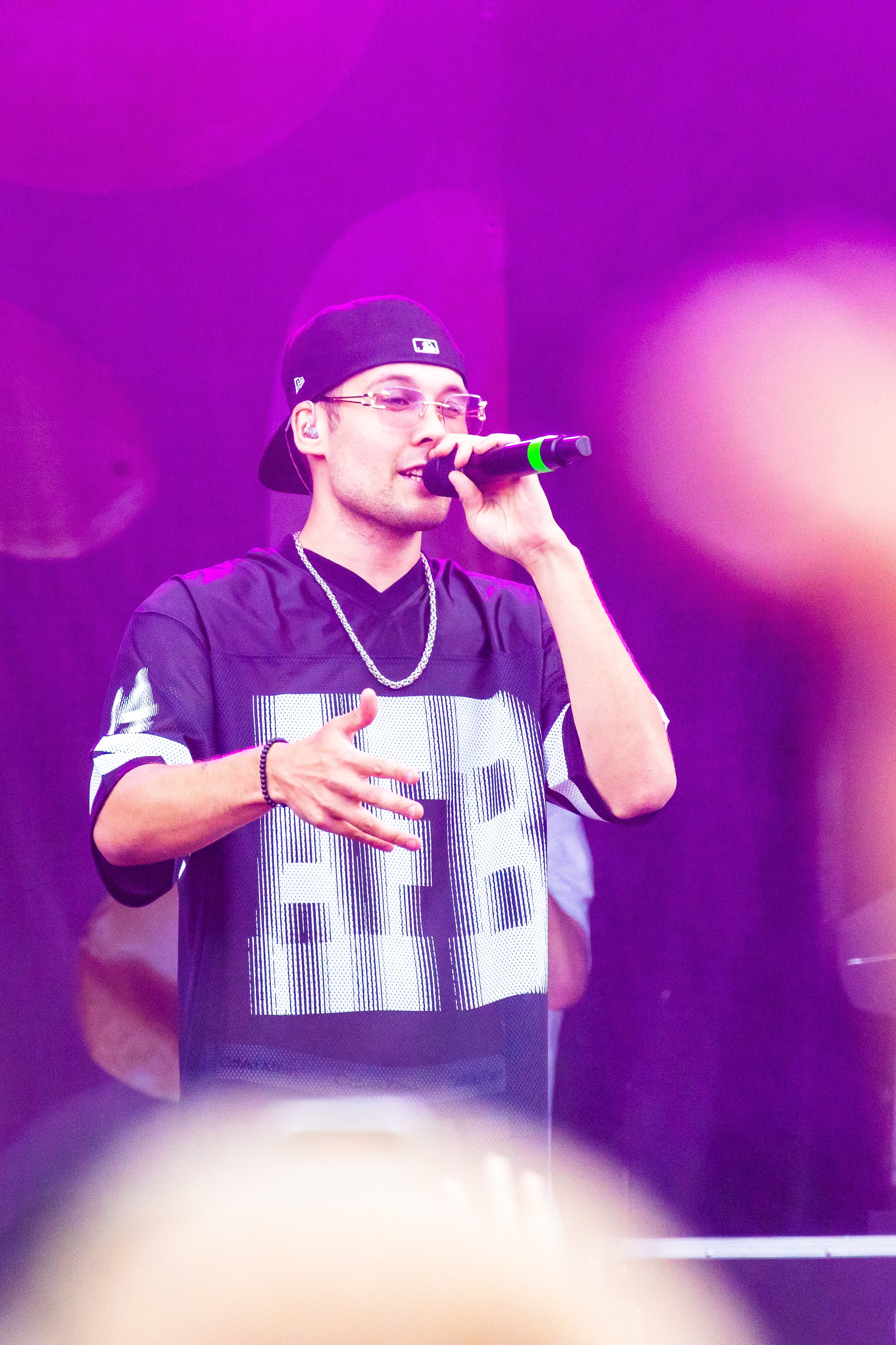 Nuori mies esittää laulua mikrofoni kädessä, taustalla kuvioitu lila-pinkki valo.