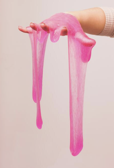 A hand stretched with pink slime hanging from the fingers