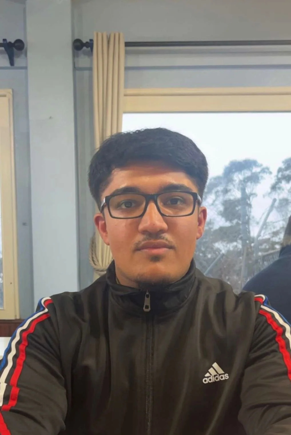 Illustration of a person with short black hair, tan skin, and a beige shirt, set against a red circular background.