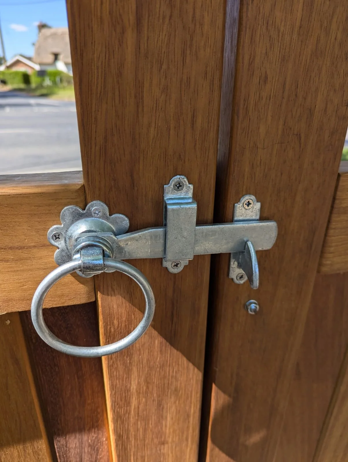 A wooden door secured with a metal latch and ring lock.