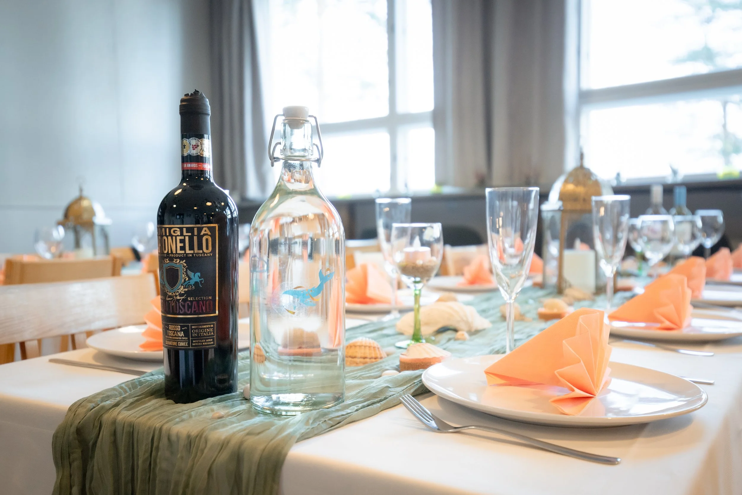 Juhla- tai juhlapöytään aseteltu pöytä, jossa on lasit, lautasia ja käännetyt ruudulliset servietit.