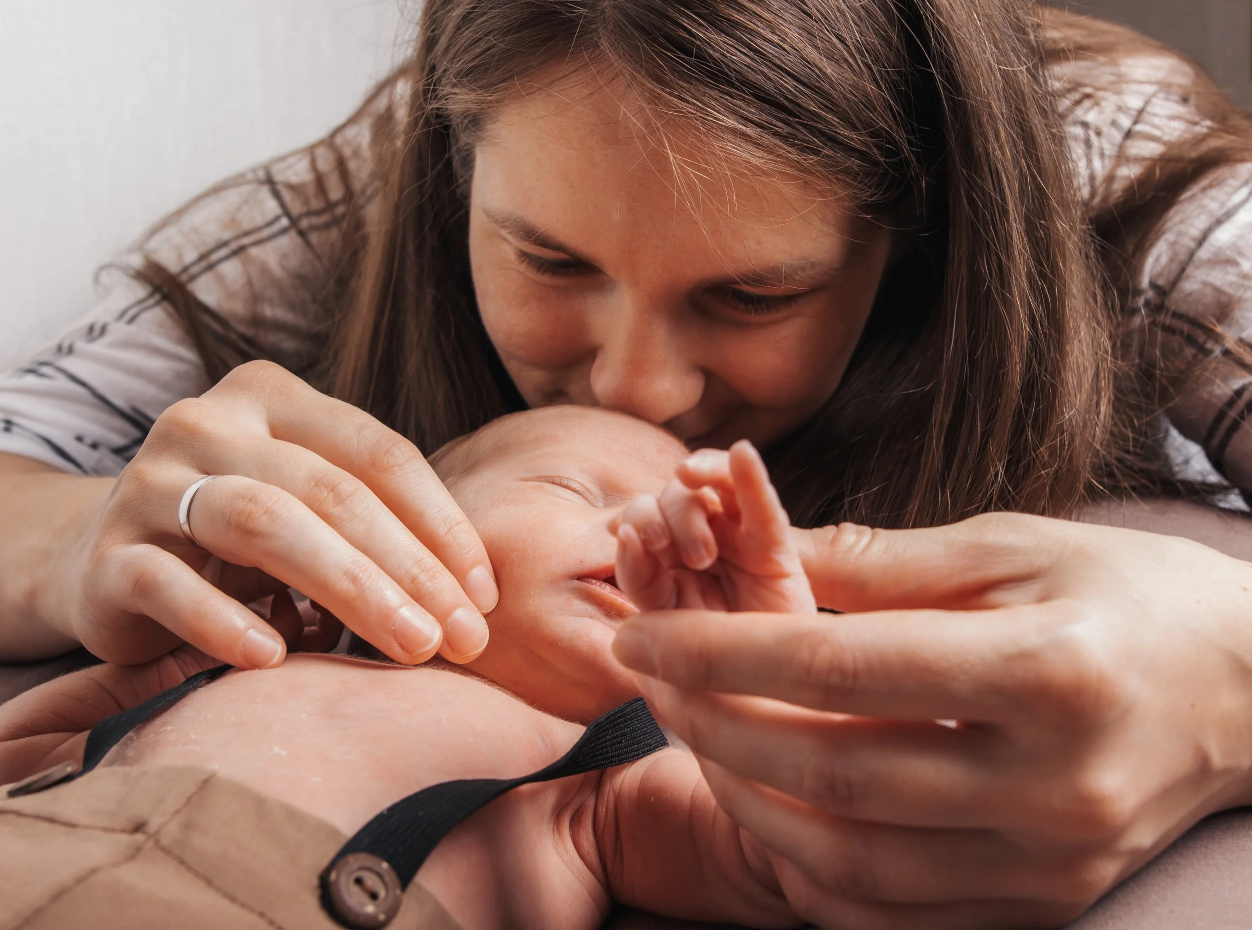 Nainen suuteli ja hyväilee vastasyntynyttä lasta, joka makaa pehmeällä säkkituolilla