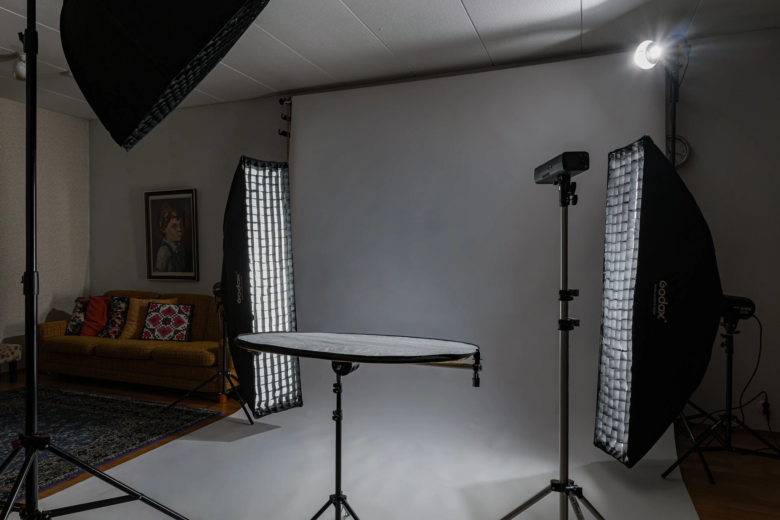 Valokuvakamera- ja valonlähdetyötila, studiolaitteet ja verhoiltu sohva