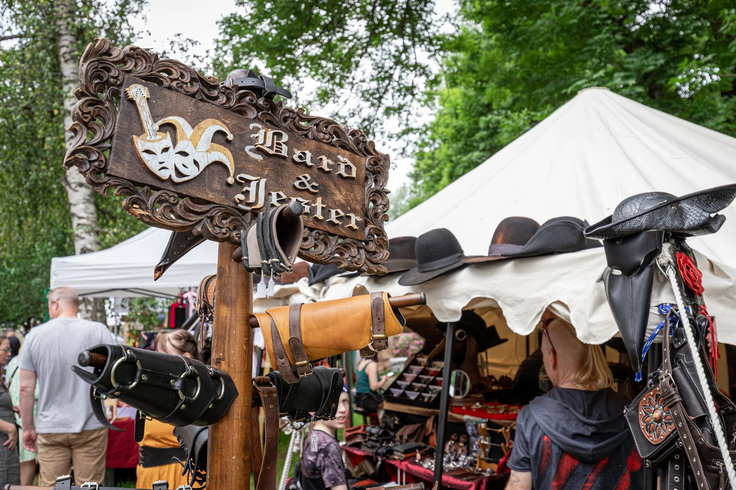 Myyntikoju, jossa on erilaisia hattoja ja nahkatarvikkeita, sekä kyltti 'Bard & Jester'.