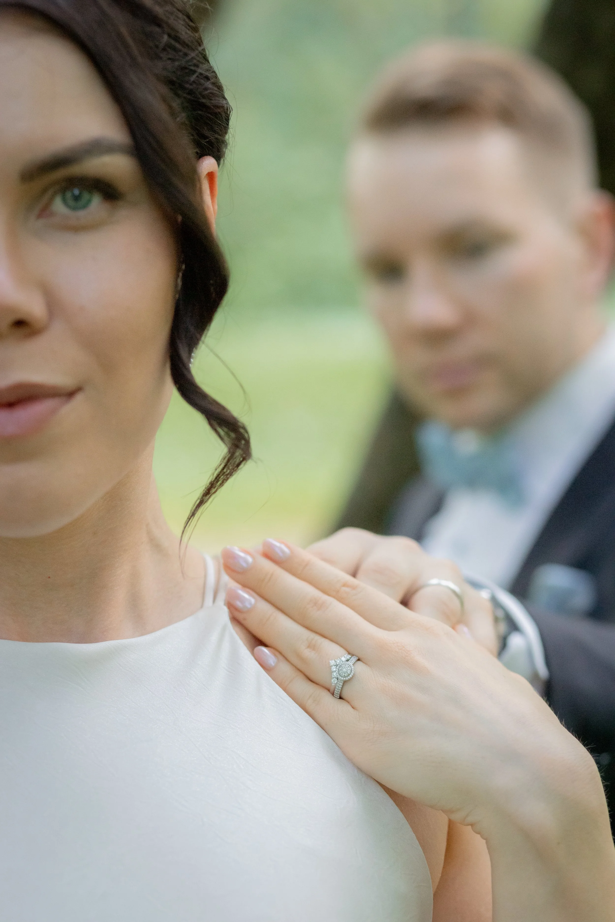Hääparin lähempää, näkyvissä vain osa morsiamen kasvoista ja jalkapohjat. Morsaimen oikealla kädellä on sormus, ja hänen vaatteensa ovat valkoiset.