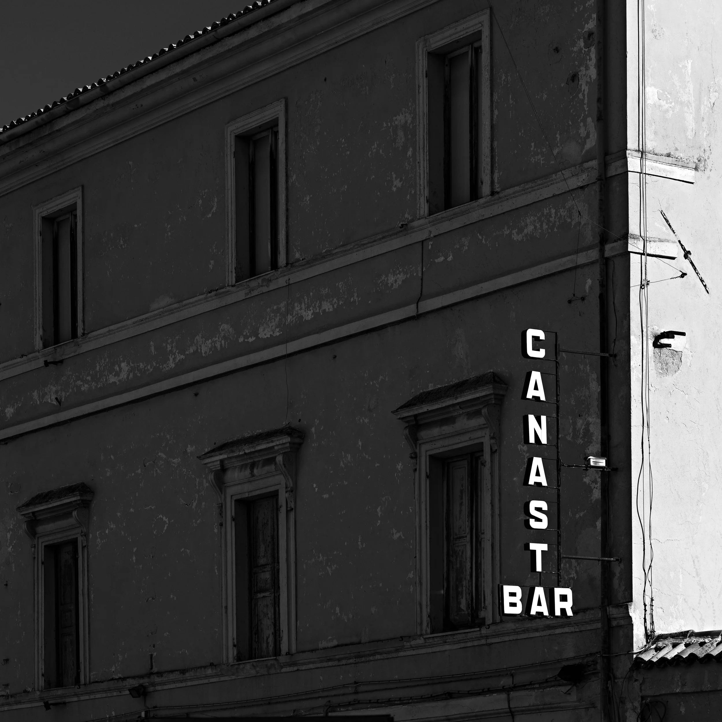 Old building with a vertical neon sign that reads 'CANASTA BAR' against a dark sky.