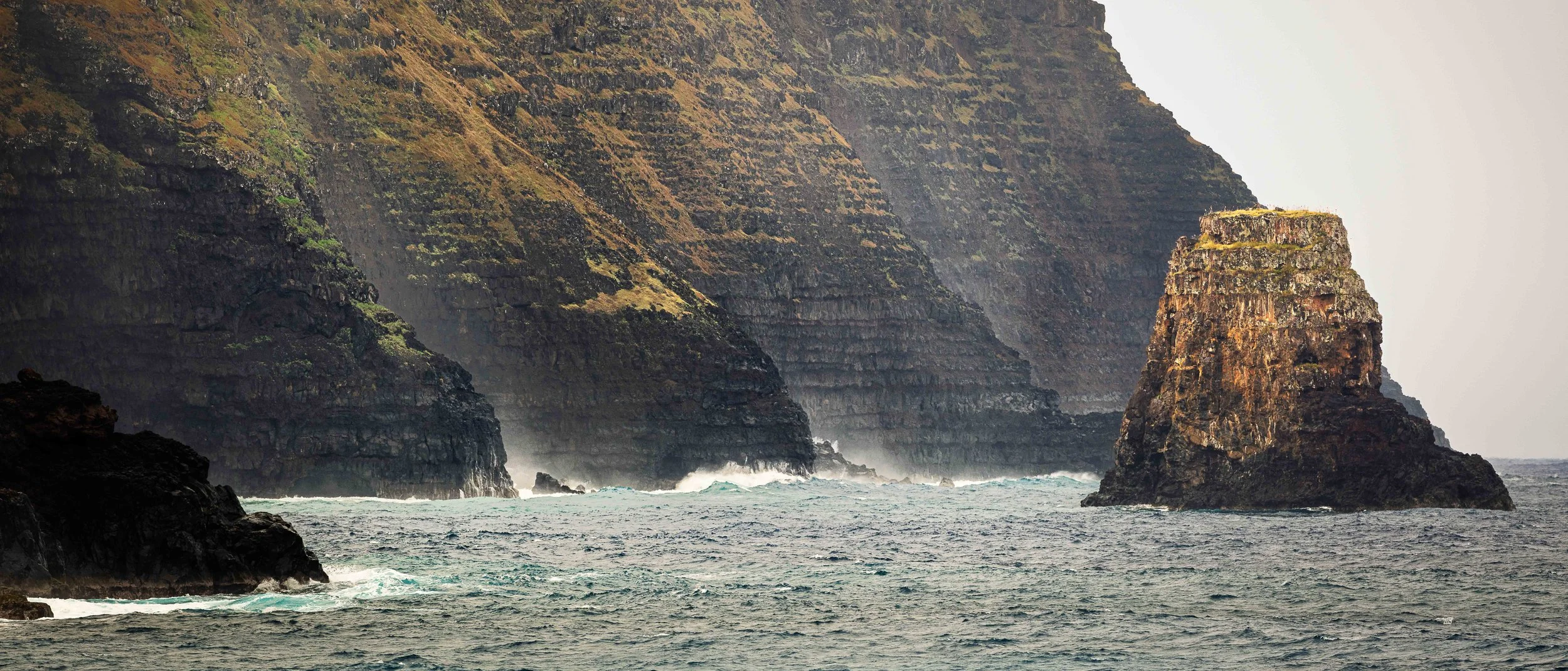 Cliffside coastline with towering rock formations and waves crashing against the rocks in the ocean