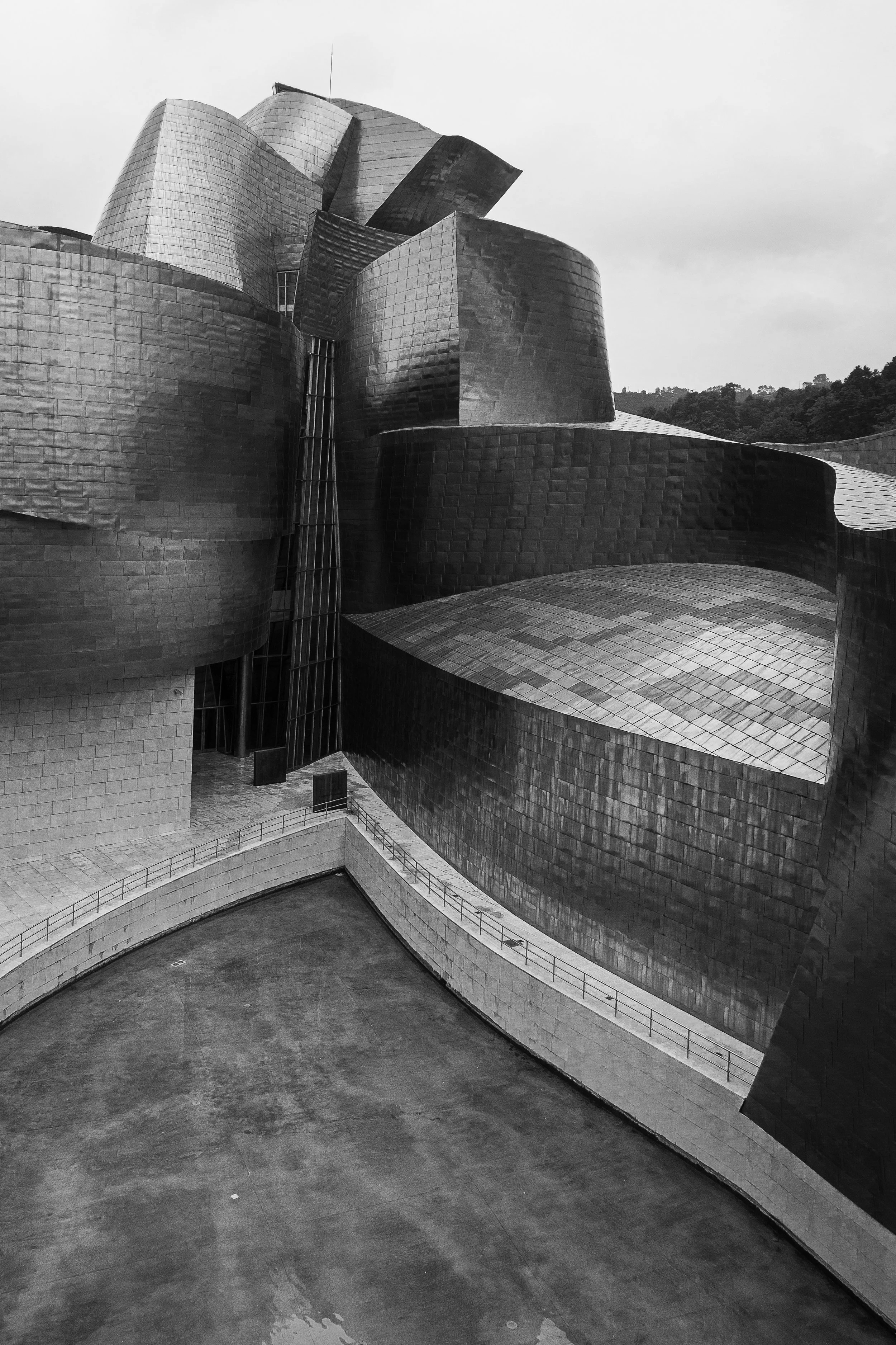 Black and white photo of a modern, abstract building with metal panels and curved surfaces.