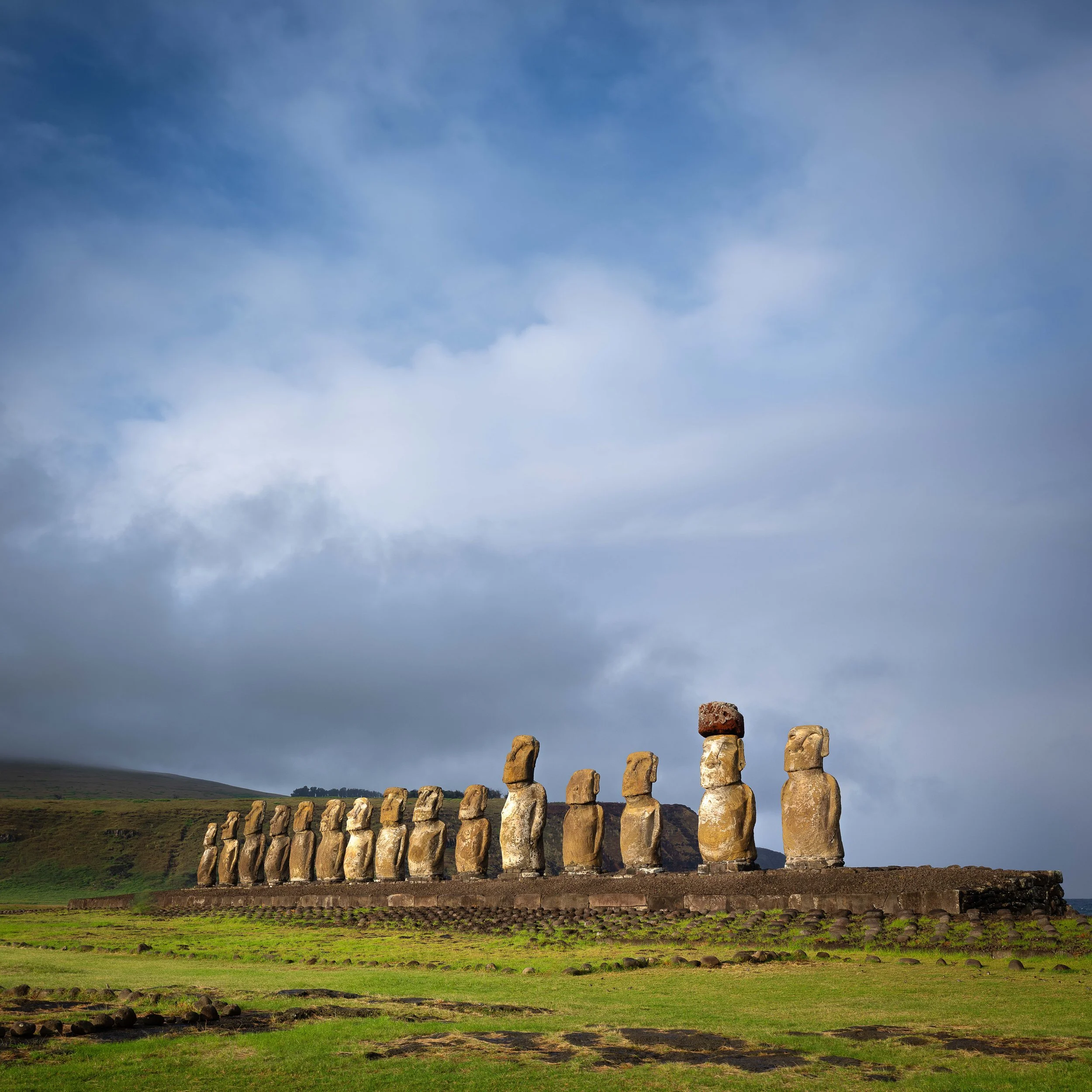 Several moai statues on Easter Island, with a cloudy sky in the background.