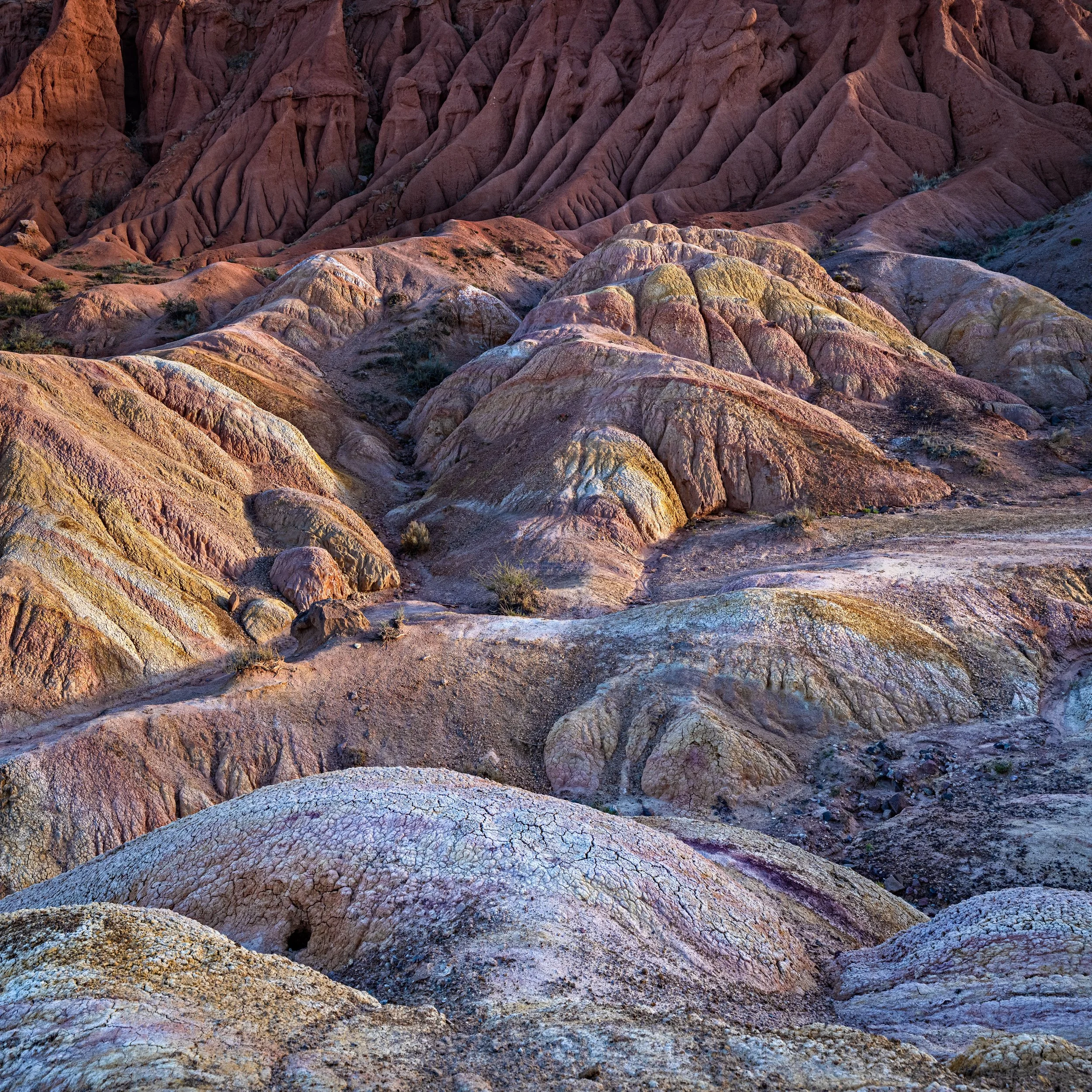 Colorful, rugged desert landscape with multicolored layered rocks and eroded formations.