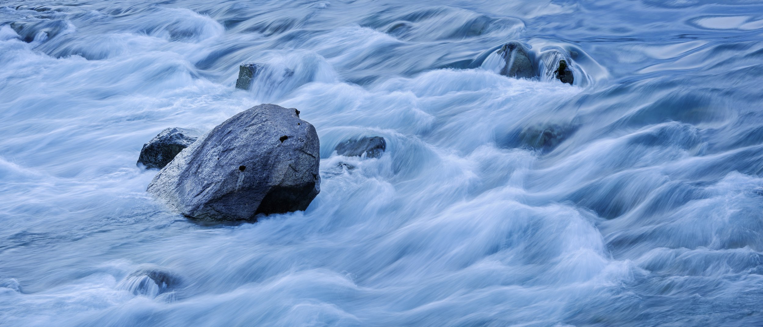Flowing river water around rocks, with a long exposure effect creating a smooth appearance.