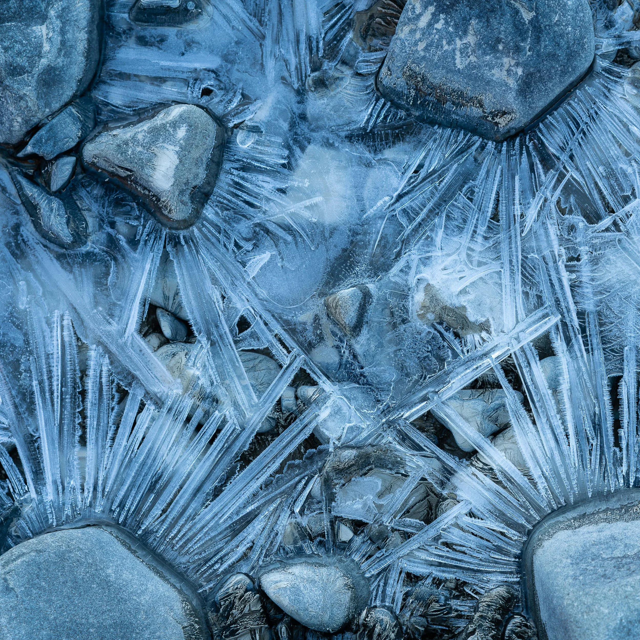Close-up of rocks with intricate frost patterns forming on the surface, creating a crystalline design over the stones.