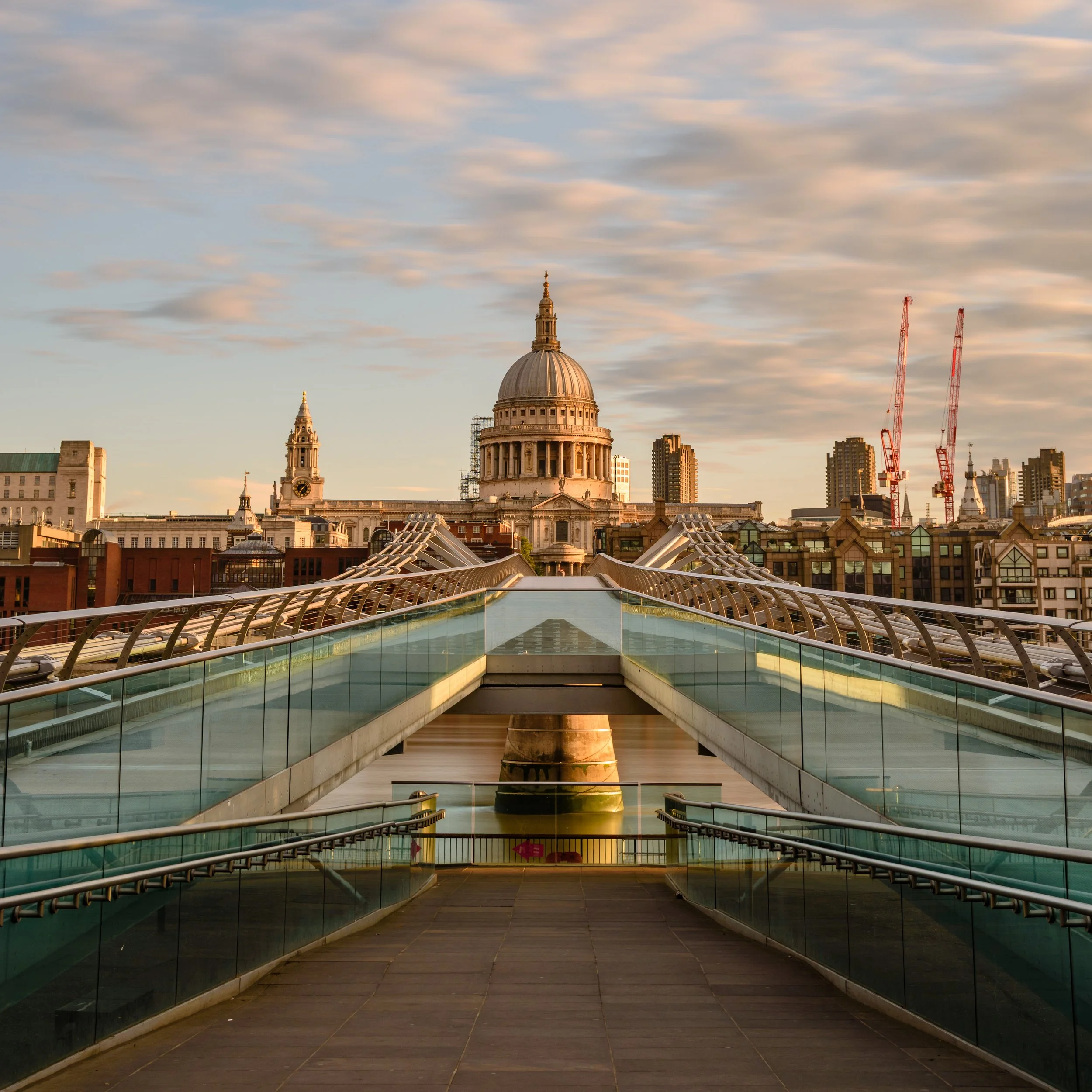 Cityscape view with a glass bridge leading towards St. Paul's Cathedral in London during sunset.