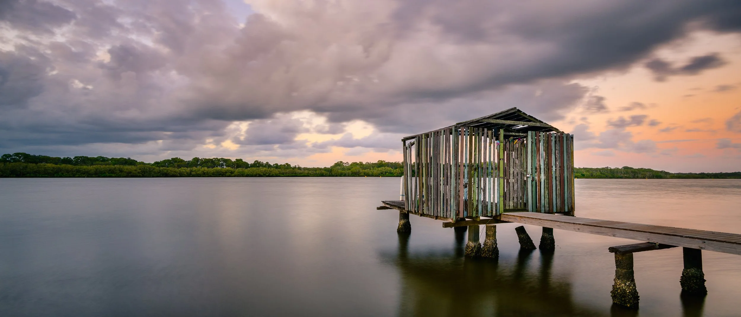 Long exposure sunrise of quirky colorful fishing shack and jetty on smooth waters of Maroochy River | Brisbane landscape and travel photographer Ralph McConaghy