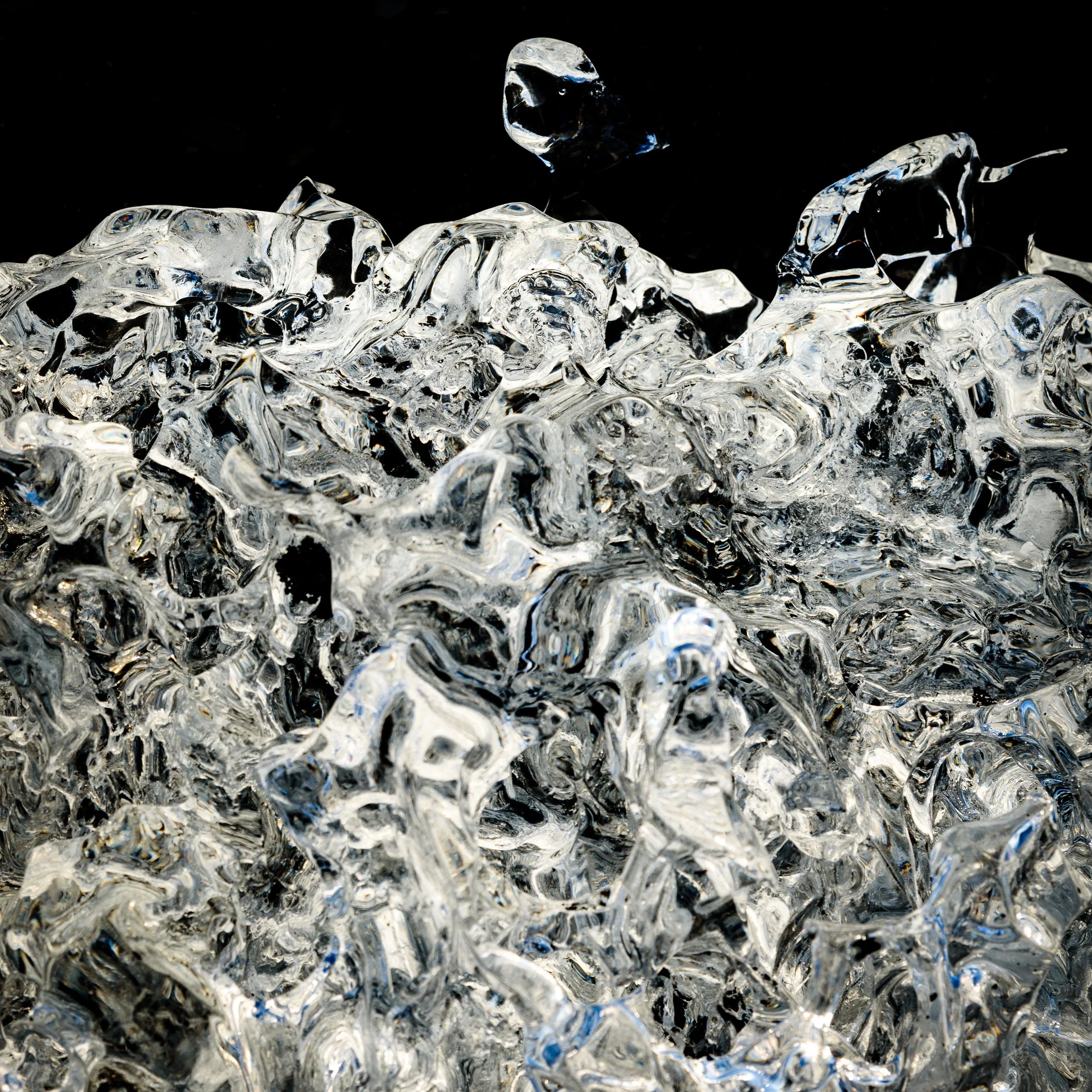 Close-up of tangled, shiny, ice against a black beach background.