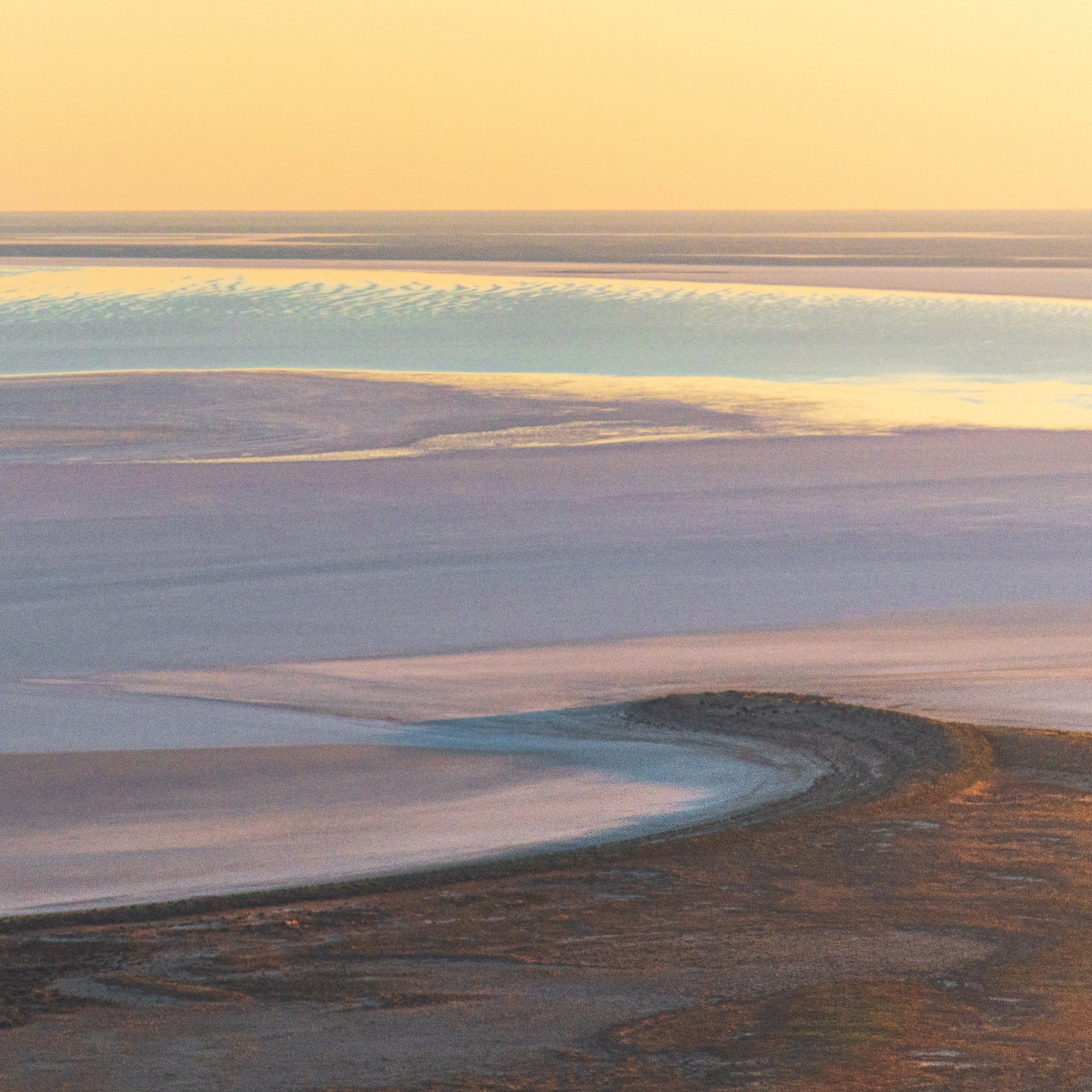 A serene beach landscape during sunset, with gentle waves lapping against the shoreline and a soft, colorful sky overhead.