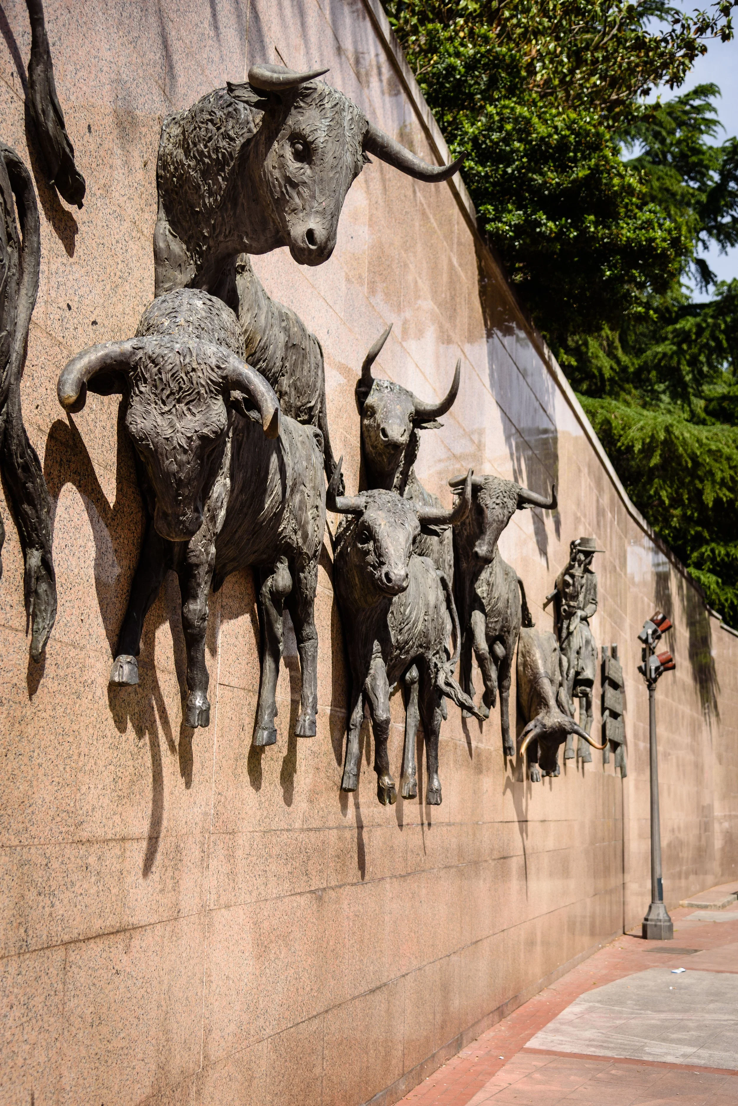 Bronze sculptures of various animals including bulls, oxen, and a buffalo mounted on a brick wall.