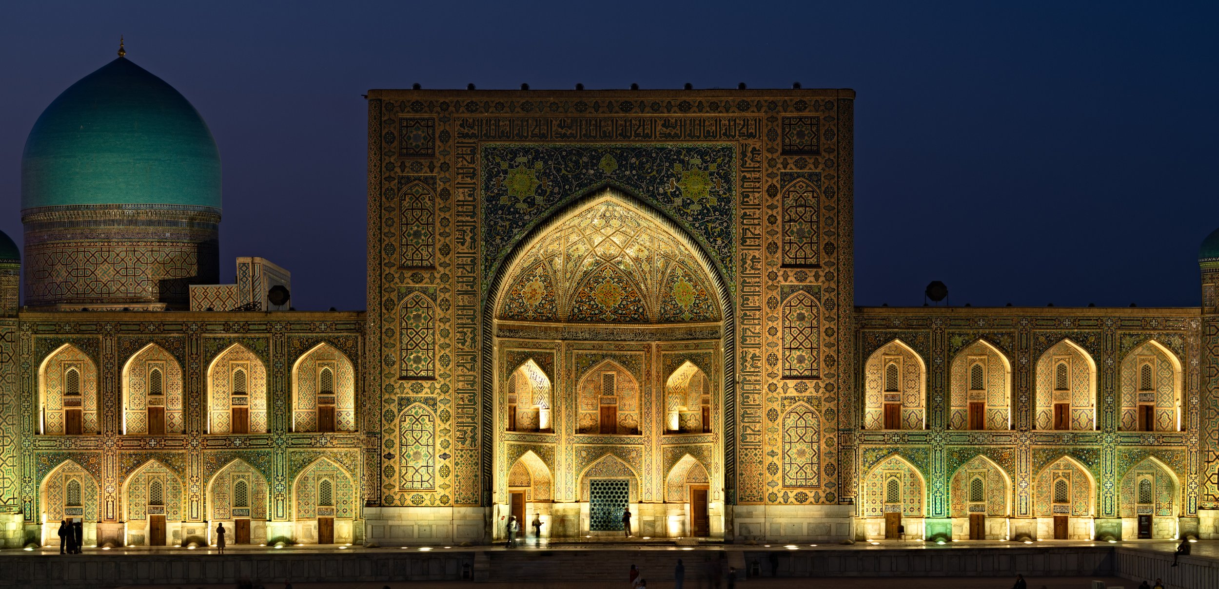 Illuminated historic Islamic architectural building at night with intricate tile work and domed roofs.